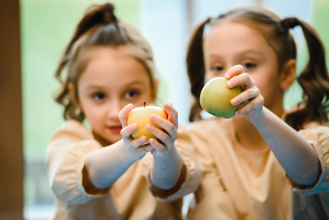 A pair of children holding apples